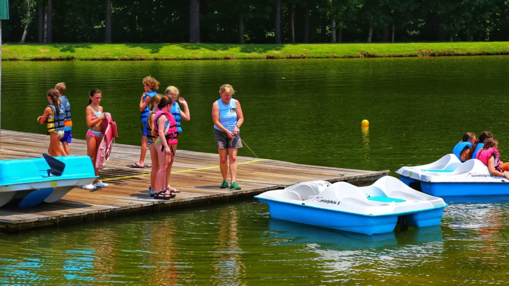 recreationists gather on a dock, with paddleboats nearby, enjoying the type of outdoor activities available in Alabama