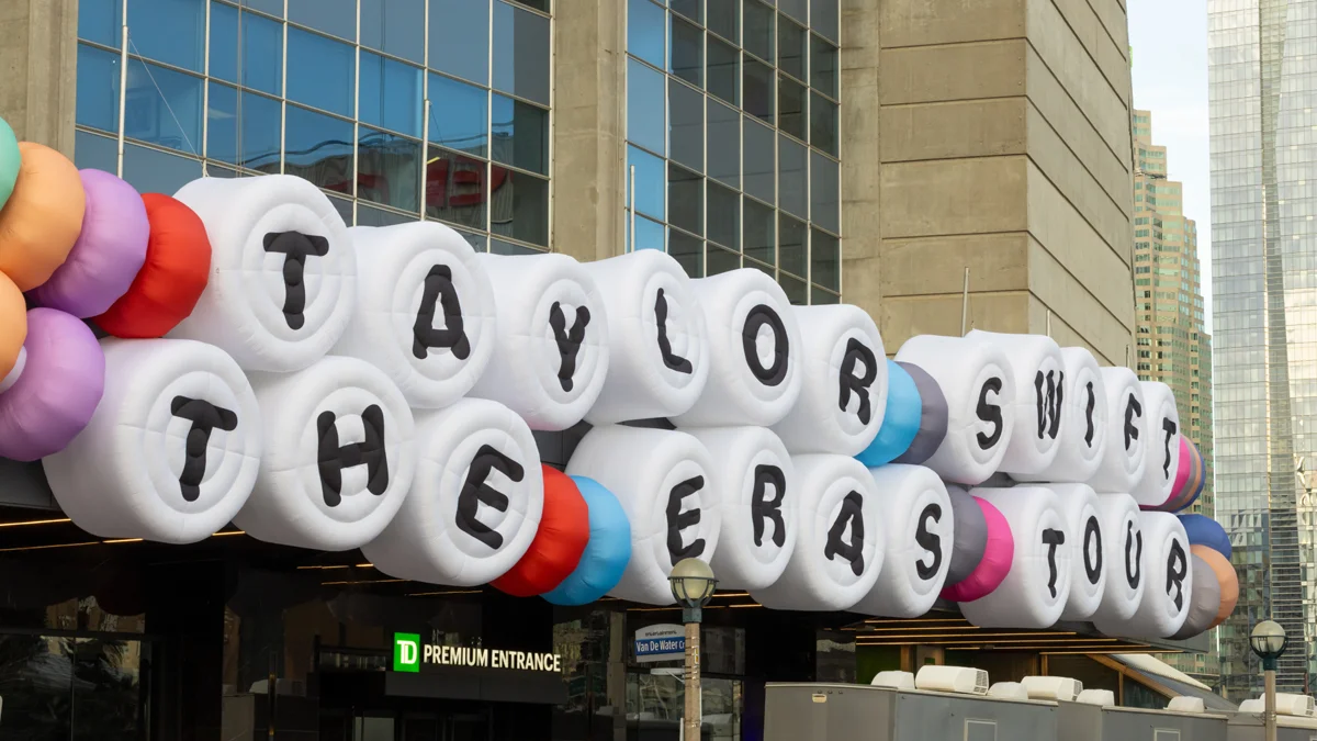 Taylor Swift The Eras Tour sign displayed outside an event venue with colorful inflatable decorations.